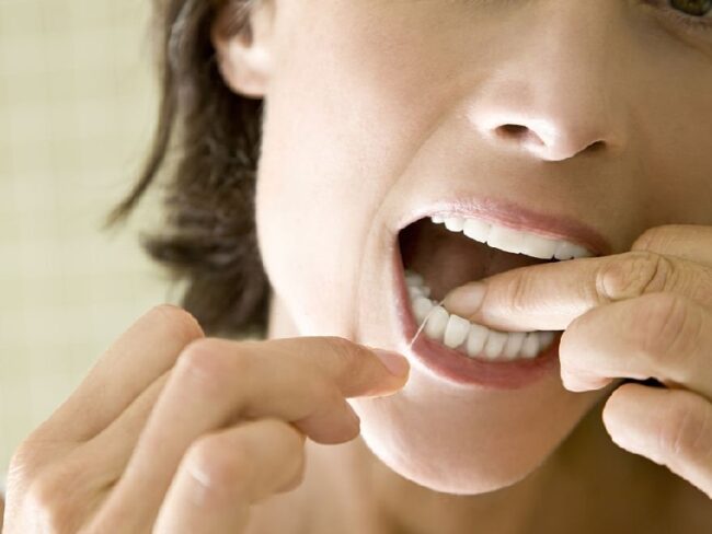 close up of woman flossing her teeth.
