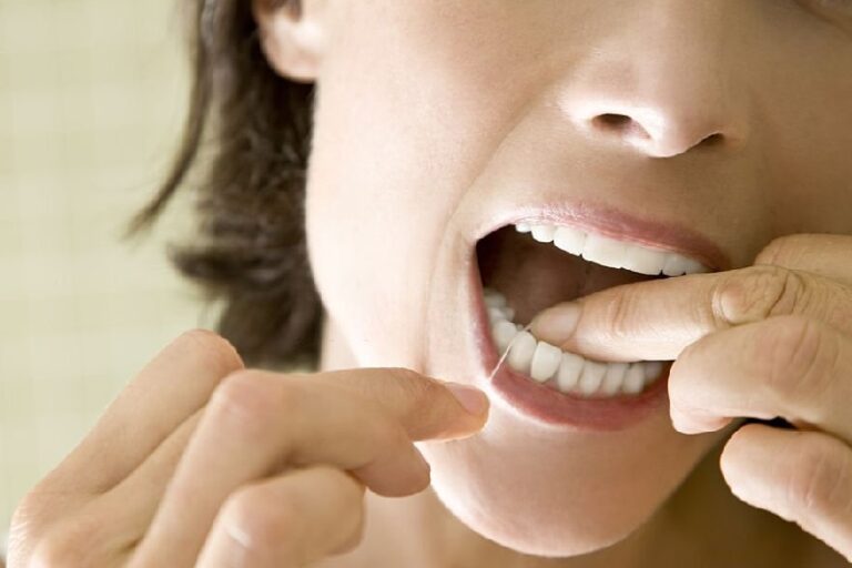 close up of woman flossing her teeth.